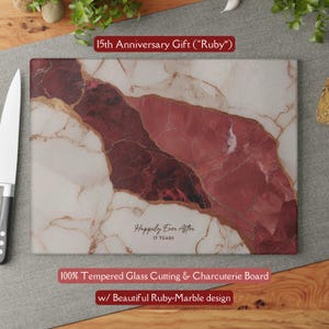 May include: A rectangular tempered glass cutting board with a ruby-marble design. The board has a white background with red and gold veining. Text on the board reads "Happily Ever After 15 YEARS".
