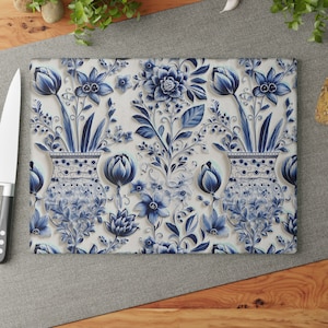 Peut inclure: Planche à découper en verre avec un motif floral bleu et blanc. Le motif présente un motif répétitif de vases avec des fleurs, des feuilles et des tiges.
