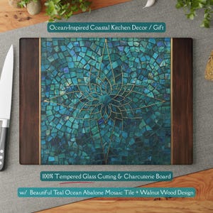 May include: A rectangular cutting board with a teal mosaic tile design and walnut wood accents. The mosaic features a gold floral pattern in the center. The text "Ocean-Inspired Coastal Kitchen Decor / Gift" is at the top. The text "100% Tempered Glass Cutting & Charcuterie Board" is at the bottom.