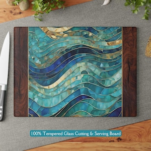 May include: A tempered glass cutting and serving board with a blue, green, and gold abstract wave pattern. The board has a dark wood frame.