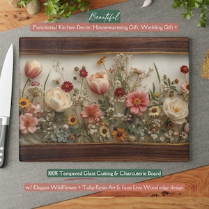 May include: A rectangular glass cutting board with a floral design. The board has a clear surface with embedded flowers, including tulips and wildflowers. The edges are framed with dark wood. Text on the board reads "100% Tempered Glass Cutting & Charcuterie Board".
