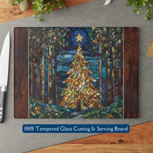 May include: Rectangular tempered glass cutting and serving board with a stained glass Christmas tree design. The board has dark wood trim and the text "100% Tempered Glass Cutting & Serving Board". A knife is visible on the left.