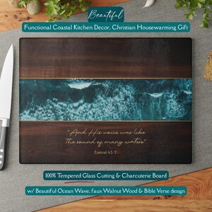 May include: Tempered glass cutting board with a faux walnut wood design and a turquoise ocean wave pattern. The board features a Bible verse and is suitable for coastal kitchen decor.
