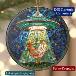 May include: A ceramic ornament with a mosaic design featuring a chicken under a green and gold UFO. The background is blue with star accents. Text on the ornament reads "100% Ceramic Ornament" and "Funny Keepsake". Includes a gold hanging string.