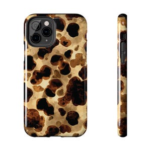 May include: A phone case with a tortoiseshell pattern. The case features a repeating pattern of dark brown and tan shapes against a light tan background. The case has a glossy finish and a camera cutout.