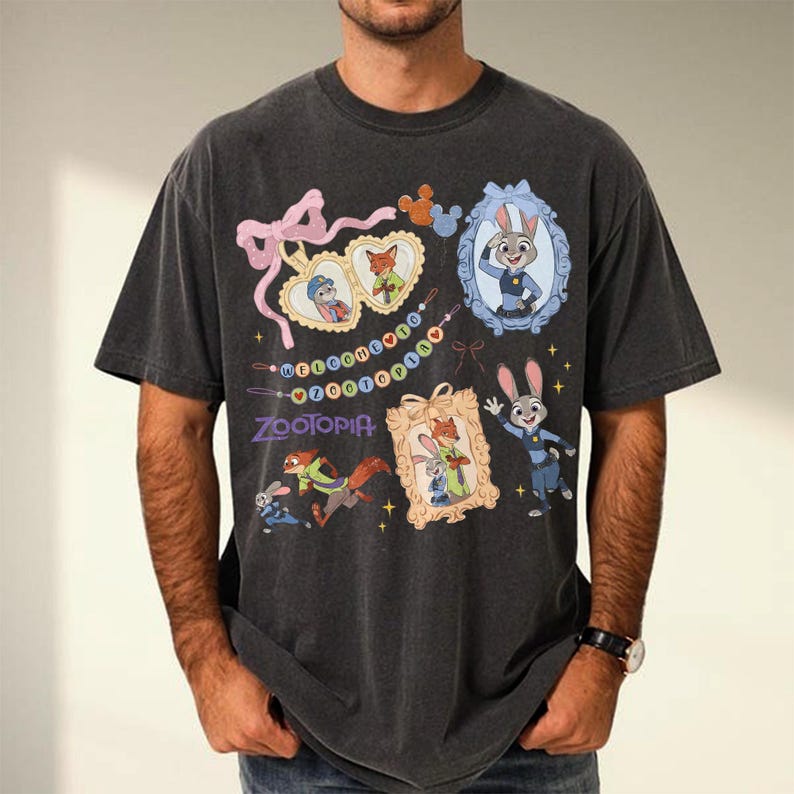 May include: Dark grey t-shirt with Zootopia characters and designs. The graphic includes framed portraits of Judy Hopps and Nick Wilde, plus the word "Zootopia". The shirt has a vintage, washed appearance.