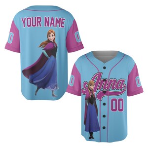 May include: Light blue baseball jersey with pink sleeves and accents. The jersey features the name "Anna" in script on the front and the image of a character. The back of the jersey has the text "YOUR NAME" and a character image.