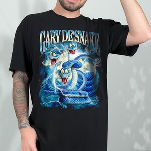 May include: Black t-shirt featuring a vibrant graphic of blue snakes with lightning bolts and the text "GARY DESNAKE" in a stylized font. The snakes have cartoonish expressions, adding a playful element to the design.