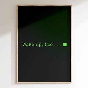 May include: A framed poster with the text "Wake up, Neo..." in green against a black background. A small green square is to the right of the text. The poster is in a wooden frame and is hanging on a white wall.