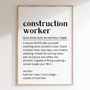 Puede incluir: Una impresión enmarcada en blanco con una definición en blanco y negro de un trabajador de la construcción. La definición dice: "una carretilla elevadora humana que puede construir cualquier cosa mientras está cubierta de polvo. Dominio de herramientas eléctricas, cinta adhesiva y palabrotas creativas. Conocido por convertir el caos en estructuras y el café en milagros. Capaz de arreglar cualquier cosa, excepto quizás tu Wi-Fi. Ver también: ninja del martillo | lanzador de ladrillos | maestro de los sombreros duros"