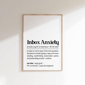 Könnte beinhalten: Gerahmter Druck mit dem Text "Inbox Anxiety" in fetter schwarzer Schrift. Die Definition und Symptome von Inbox Anxiety sind unter dem Titel aufgeführt. Der Rahmen ist hellbraun.