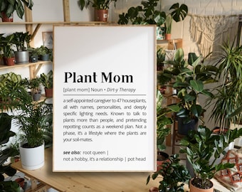 Puede incluir: Un cartel enmarcado con las palabras "Plant Mom" en negrita negra. La definición describe a un entusiasta de las plantas. El cartel está rodeado de varias plantas en macetas, creando un ambiente exuberante y verde.