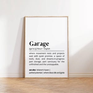 Op de afbeelding: Een zwart-witte printbare kunstprint met de definitie van het woord "Garage". De definitie luidt: "Waar beweging rust en projecten wachten met stille belofte. Een ruimte voor gereedschap, stof en dromen in uitvoering, een deel opslagruimte, een deel heiligdom voor het onvoltooide en het onstuitbare. Zie ook: knutselparadijs | Geparkeerd potentieel | Waar ideeën stilliggen en ontbranden"