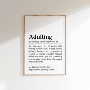 以下が含まれることがあります： 「Adulting」の定義が書かれた額入りのプリント。定義には、請求書の支払い、歯医者の予約、洗濯物の折り畳み、野菜を食べたことへの自己賞賛といった、甘く切ない芸術が含まれています。