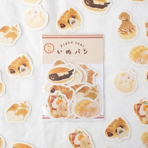 May include: A sheet of 8x3 inch stickers featuring adorable cartoon dogs in various bread-themed poses. The stickers are labelled "Flake seal" and "いぬぱん" in Japanese.