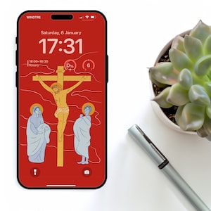 Könnte beinhalten: Ein roter Smartphone-Bildschirm zeigt eine Digitaluhr mit der Zeit 17:31, dem Datum Samstag, 6. Januar, und den Text "Rosary" mit der Zeit 18:00-18:30. Das Hintergrundbild ist eine religiöse Szene, die Jesus Christus am Kreuz mit zwei Figuren darstellt, die auf beiden Seiten des Kreuzes stehen.