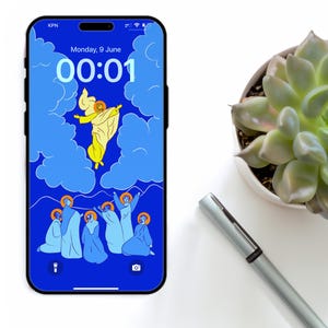 Puede incluir: Un smartphone con pantalla azul que muestra una ilustración religiosa. La obra de arte representa una figura amarilla ascendiendo a las nubes, rodeada de figuras con túnicas azules. La hora es 00:01. También se ven una planta suculenta y un bolígrafo.