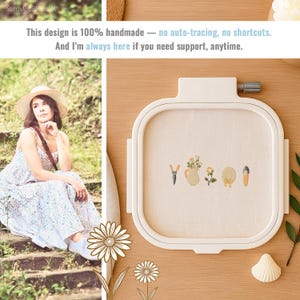 May include: A white embroidery hoop with a cream-colored fabric featuring embroidered garden-themed designs. The design includes a pair of shears, a vase of flowers, a flower, a hat, and a trowel. Text on the image reads: "This design is 100% handmade - no auto-tracing, no shortcuts."