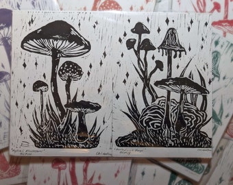 May include: Two black and white linocut prints of mushrooms. The print on the left is titled "Mystical Mushrooms" and the print on the right is titled "Fantastic Fungi".