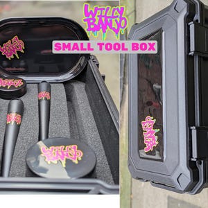 May include: Black tool box containing a matching set of accessories. The set includes a tray, grinder, and three cylindrical tools. Each item features a pink and yellow logo. The text "SMALL TOOL BOX" is displayed on the box.