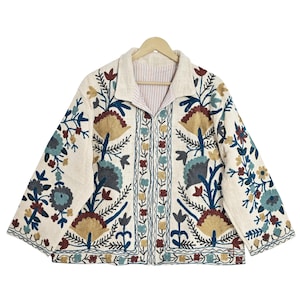 May include: Cream-colored jacket with intricate floral embroidery in shades of blue, gold, and burgundy. The jacket features a collared neckline and a striped lining. The embroidery is detailed and covers the front, sleeves, and back of the jacket.
