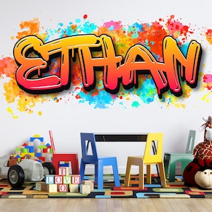 Puede incluir: Adhesivo de pared colorido con el nombre "ETHAN" en estilo grafiti, con un degradado de naranja, amarillo y rojo. El fondo tiene salpicaduras de pintura de varios colores. La habitación tiene una mesa, sillas, juguetes y una alfombra.