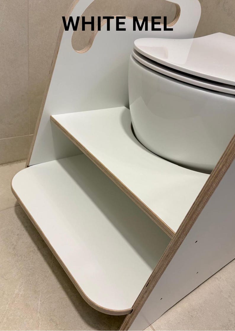 Pode incluir: Um banco de dois degraus branco com bordas de contraplacado, apresentando o texto WHITE MEL impresso no painel lateral superior. A estrutura inclui um recorte de al&ccedil;a no topo e um acabamento de superf&iacute;cie branco liso nos degraus.