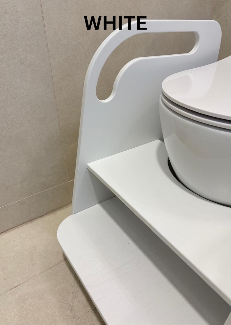 Pode incluir: Um banco de degrau de madeira branco com acabamento liso e uma al&ccedil;a recortada no topo. A estrutura apresenta uma plataforma plana e um painel lateral curvo. A palavra WHITE est&aacute; impressa em preto no topo da estrutura, perto da al&ccedil;a.
