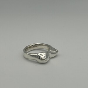 May include: A silver ring with a unique design featuring two raised bumps on the top.
