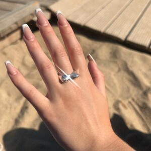 May include: A silver ring with a unique, abstract design. The ring is shaped like two rounded, connected forms.