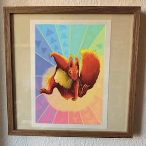 Könnte beinhalten: Ein gerahmter Druck eines roten Eichhörnchens mit gelbem Bauch, das vor einem Regenbogenhintergrund mit einem Muster aus Dreiecken springt.