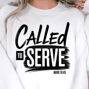 May include: White sweatshirt featuring the phrase "Called to Serve" in a striking black font, set against a black brushstroke. The text "Mark 10:45" is printed below the main text, all on a white background.