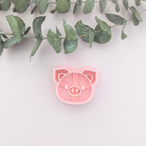 May include: Pink plastic pig cookie cutter with a detailed design.