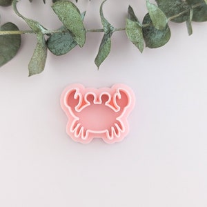 Puede incluir: Un cortador de galletas de plástico rosa en forma de cangrejo.
