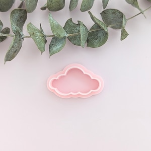 Puede incluir: Un cortador de galletas en forma de nube de plástico rosa.