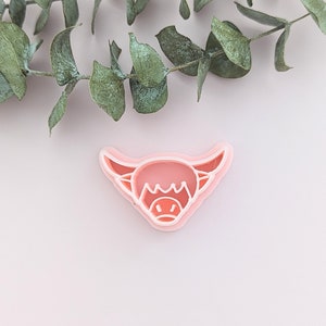 May include: A pink plastic cookie cutter shaped like a Highland cow head.