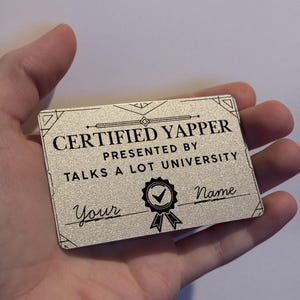 Könnte beinhalten: Eine silberfarbene Urkunde mit schwarzem Text. Sie lautet "CERTIFIED YAPPER" und "TALKS A LOT UNIVERSITY". Die Urkunde hat einen dekorativen Rahmen und ein Siegel mit einem Häkchen. Die Wörter "Your" und "Name" stehen ebenfalls auf der Urkunde.