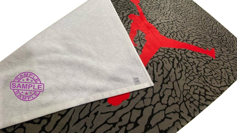 Pu&ograve; includere: Asciugamano bianco con stampa di elefante rosso e grigio. L'asciugamano ha un timbro viola "SAMPLE".