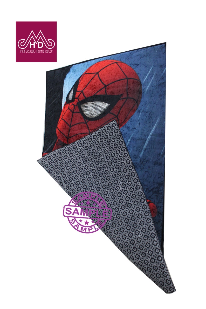 Puede incluir: Una alfombra azul y roja con una imagen de dibujos animados de la cara de Spiderman. La alfombra tiene un patr&oacute;n geom&eacute;trico en blanco y negro en la parte posterior.