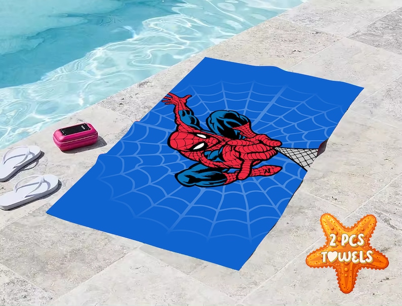 Pu&ograve; includere: Due asciugamani da spiaggia blu con un design Spiderman rosso e blu e un motivo a ragnatela bianca. Il testo "2 PCS TOWELS" &egrave; su una stella marina.