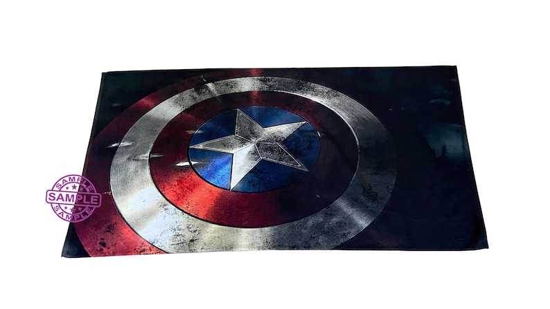 Pu&ograve; includere: Un primo piano dello scudo di Capitan America, con un design rosso, bianco e blu. Lo scudo &egrave; fatto di metallo e ha un aspetto usurato e invecchiato.