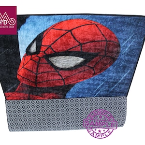 Puede incluir: Una alfombra azul y roja con una imagen de primer plano de la cara de Spider-Man. La alfombra tiene un borde negro y un borde con estampado gris y blanco.