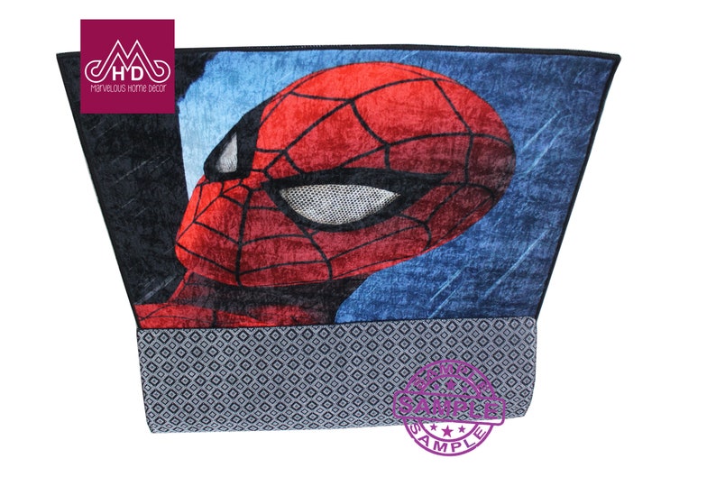 Puede incluir: Una alfombra azul y roja con una imagen de primer plano de la cara de Spider-Man. La alfombra tiene un borde negro y un borde con estampado gris y blanco.