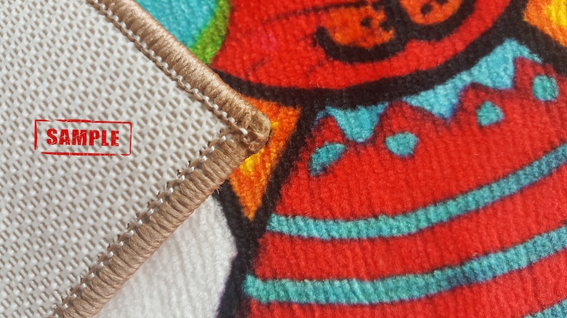 Pu&ograve; includere: Primo piano di un tappeto beige con un bordo marrone. Il tappeto ha un retro bianco con un motivo a griglia e la parola "SAMPLE" stampata in rosso. Il tappeto &egrave; piegato per rivelare un motivo colorato con accenti rossi, blu e gialli.
