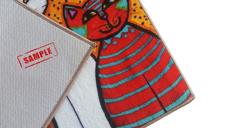 Pu&ograve; includere: Primo piano di un tappeto colorato con un design di gatto a strisce rosse e blu. Il tappeto ha un retro beige con la parola "SAMPLE" stampata in rosso.