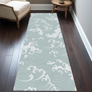 Könnte beinhalten: Ein hellblauer und weißer Teppich mit Wellenmuster. Der Teppich ist aus einem weichen, strapazierfähigen Material gefertigt und perfekt, um jedem Raum einen Hauch von Stil zu verleihen.