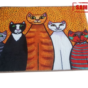 Pu&ograve; includere: Un tappeto colorato con un design di cinque gatti in piedi in fila. I gatti sono arancioni, neri, bianchi e rossi con strisce blu. Lo sfondo &egrave; di colore giallo con piccoli punti arancioni.
