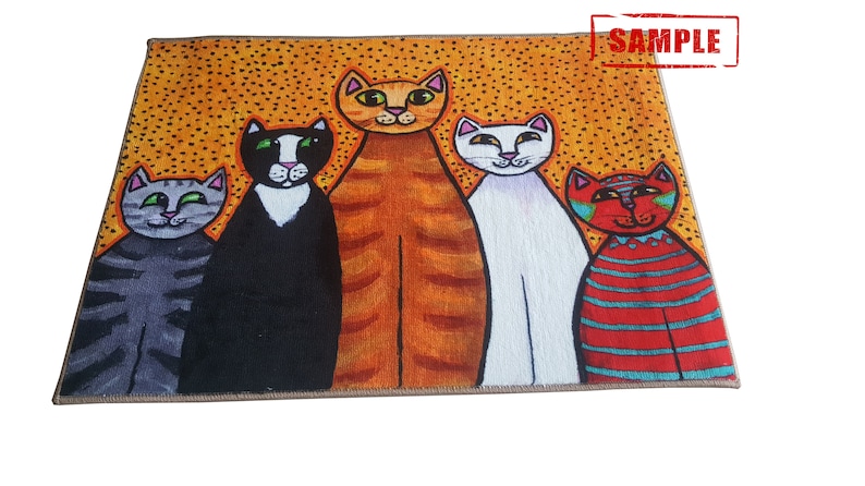 Pu&ograve; includere: Un tappeto colorato con un design di cinque gatti in piedi in fila. I gatti sono arancioni, neri, bianchi e rossi con strisce blu. Lo sfondo &egrave; di colore giallo con piccoli punti arancioni.
