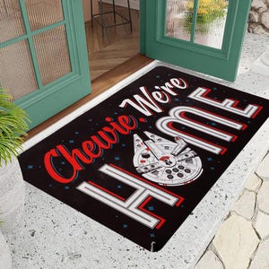 May include: Black doormat with white stars and the text "Chewie, We're Home" in red and white. A white and gray spaceship is in the center of the doormat.