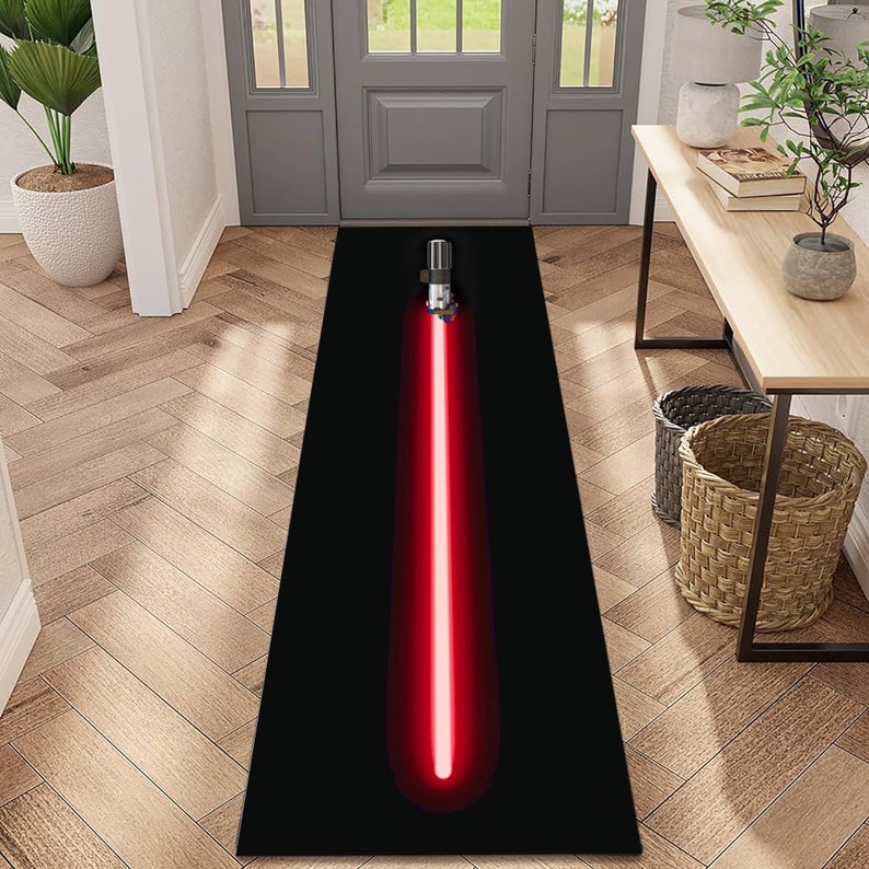 Puede incluir: Una alfombra de sable de luz negra y roja con una hoja de sable de luz roja sobre un fondo negro. La alfombra se coloca en un pasillo con suelo de madera.